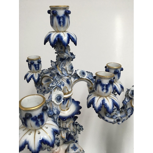 932 - A pair of Meissen candelabra with blue, white and gilt decoration o mounted with putti. 50cm. (Some ... 