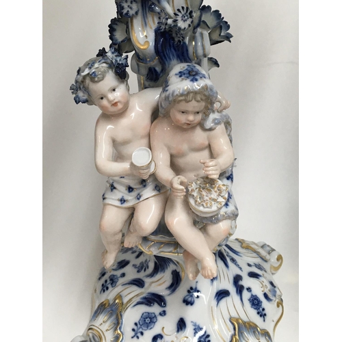 932 - A pair of Meissen candelabra with blue, white and gilt decoration o mounted with putti. 50cm. (Some ... 