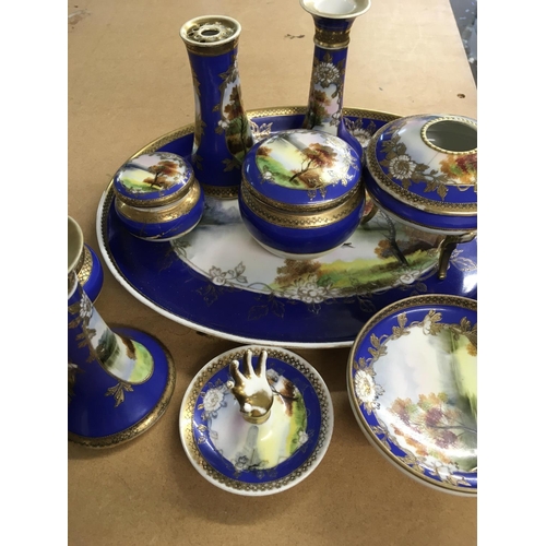 1061 - A Noritake dressing table set decorated with a landscape view in blue and gilt .