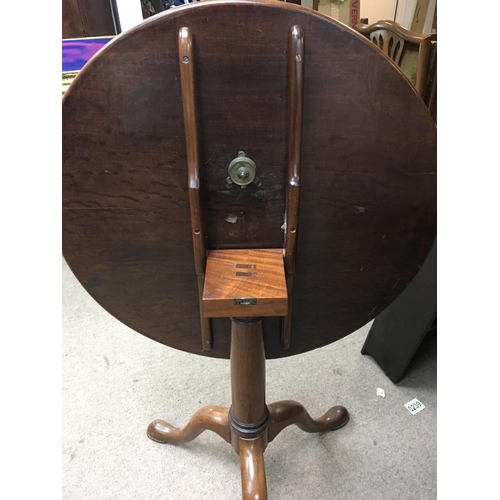 1332 - A late George III mahogany tip action table with a circular top on a turned column and splayed legs.... 