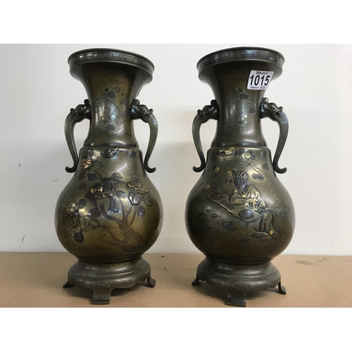 1015 - A pair of Japanese bronze vases with applied elephant handles, with raised decoration of figures, fl... 