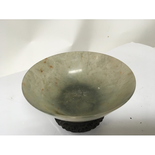 1041 - A 19th century Chinese green jade bowl with a carved hardwood stand. The bowl with stress cracks pos... 