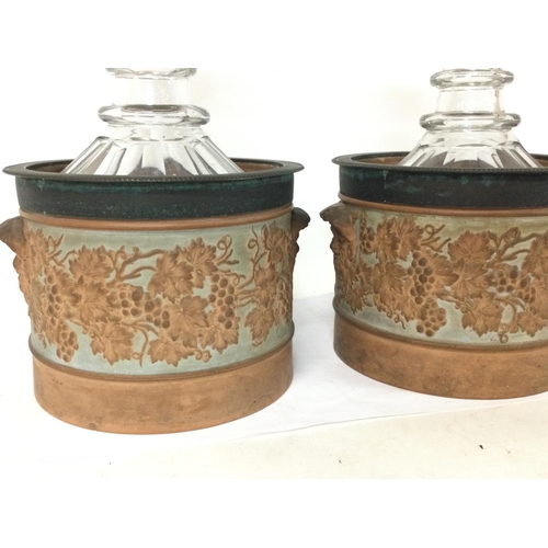 1272 - A pair of decanters housed in early 19th century sprig decorated terracotta wine coolers with plied ... 