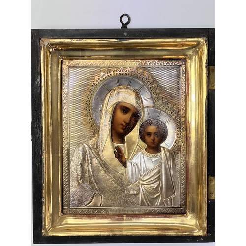 851 - A late 19thC cased Russian icon depicting the Madonna and Child with a Russian hallmarked silver cov... 