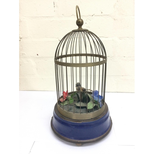 910 - Vintage small brass cage containing a single singing bird in working order.