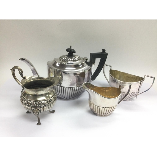 946 - A three piece silver plated tea set and a plated jug with repousse work decoration. Shipping categor... 