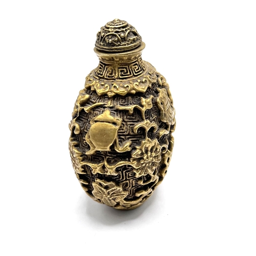 30 - A cast gilt bronze snuff bottle with decoration in the form of Buddhist symbols. Height 7cm.