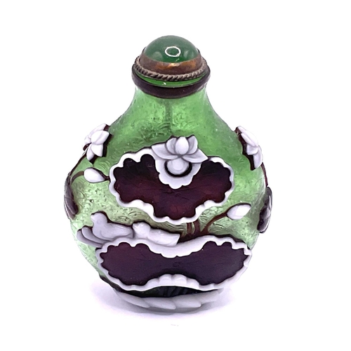 34 - A hand blow 2 layered cameo glass snuff bottle with decoration of lilys. 6.5cm.