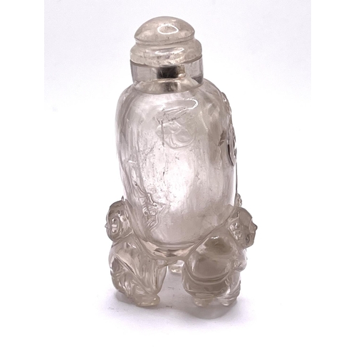 44 - A carved translucent rock crystal snuff bottle supported 3 figures. 9cm.