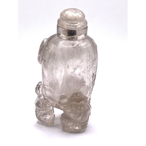 44 - A carved translucent rock crystal snuff bottle supported 3 figures. 9cm.