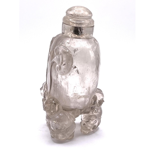 44 - A carved translucent rock crystal snuff bottle supported 3 figures. 9cm.