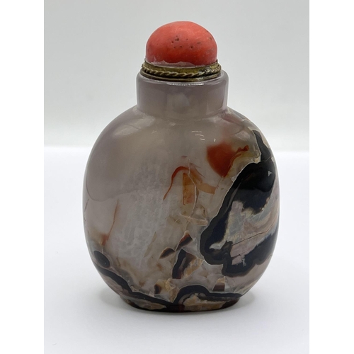 73 - A polished agate snuff bottle with a gilt metal and coral stopper. 8cm.