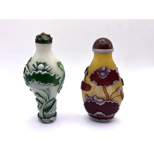 80 - 2 Chinese carved 2 colour cameo glass snuff bottle with lily pad decoration. H. 8cm / 8.5cm.