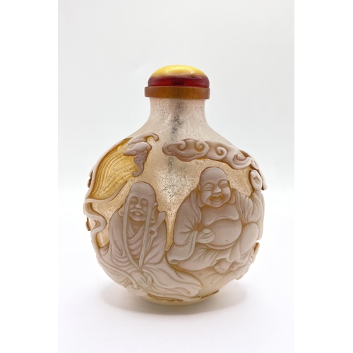 88 - A finely carved 2 layer cameo table snuff bottle depicting a happy Buddah and his followers. 12cm.