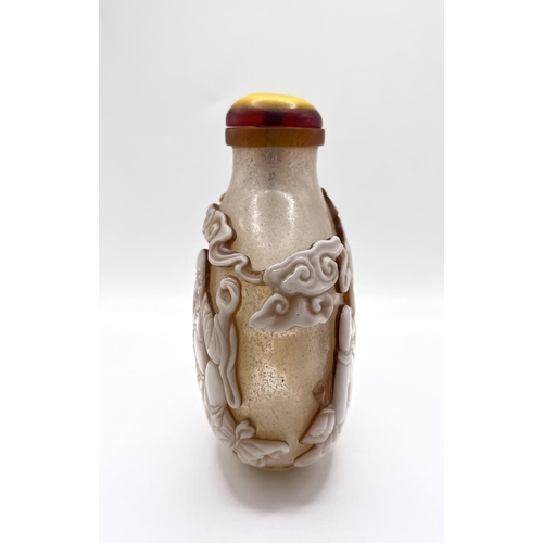 88 - A finely carved 2 layer cameo table snuff bottle depicting a happy Buddah and his followers. 12cm.