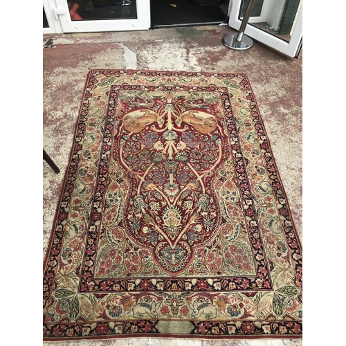 1387 - A Kirman style part silk rug depicting mythical animals on a red ground and folate border. Measuring... 