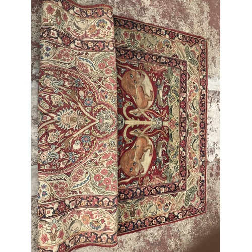 1387 - A Kirman style part silk rug depicting mythical animals on a red ground and folate border. Measuring... 