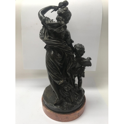 672 - A bronze figure group in classical form depicting maiden and cherub, on a marble base. 35cm in heigh... 