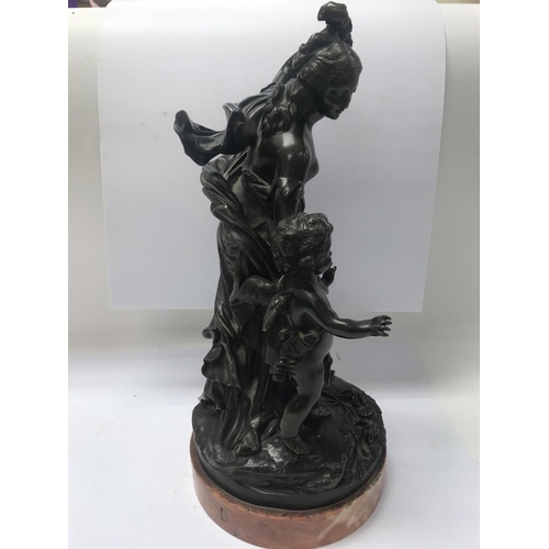 672 - A bronze figure group in classical form depicting maiden and cherub, on a marble base. 35cm in heigh... 