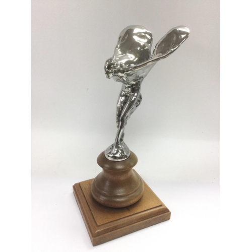 679 - A Spirit of Ecstasy car mascot raised on a wooden plinth, total height 22cm. Shipping category B.