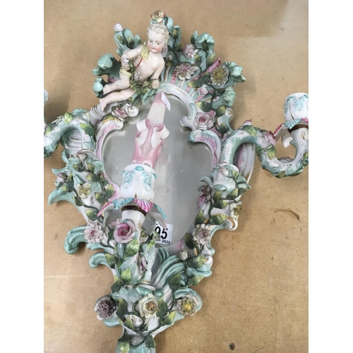 995 - A German porcelain wall mirror decorated with raised cherubs flowers and foliage with three attached... 