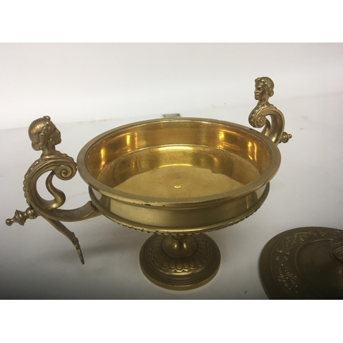 1007 - A Neo Classical gilt metal urn the lid with a raised figure flanked by scroll supports height 20cm- ... 