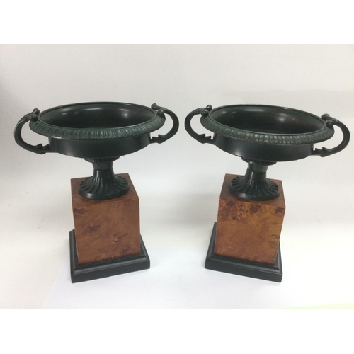 1011 - A pair of classical urns raised on squared wooden bases, approx height 20cm. Shipping category B. NO... 