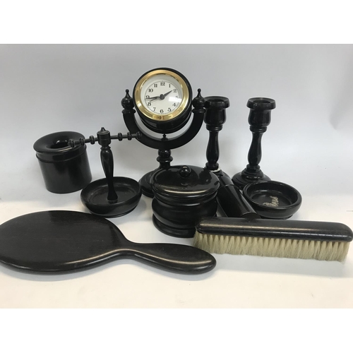 1039 - A ebonized dressing table set including clock candle sticks mirror, brush tidy jar ring tree .