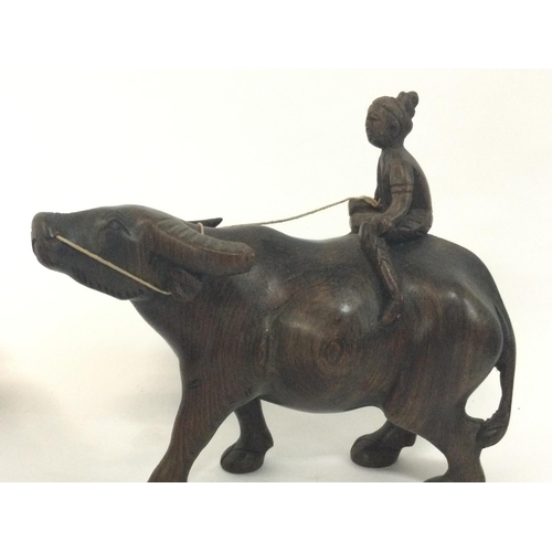 1056 - Indonesian buffalo and rider hardwood figurines, 14cm tall.