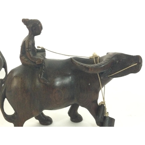 1056 - Indonesian buffalo and rider hardwood figurines, 14cm tall.