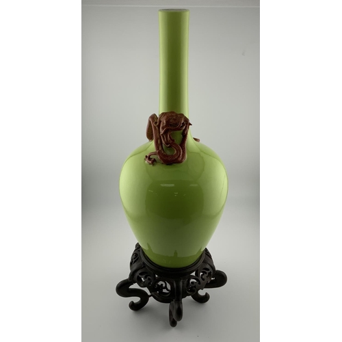 911 - A Chinese Apple green glazed monochrome bottle vase with applied dragon decoration, with a carved wo... 