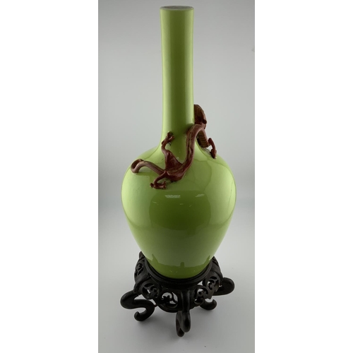 911 - A Chinese Apple green glazed monochrome bottle vase with applied dragon decoration, with a carved wo... 