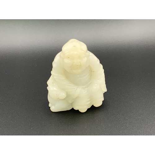 913 - A small carved jade figure of a Chinese deity seated upon a goat. 6cm.