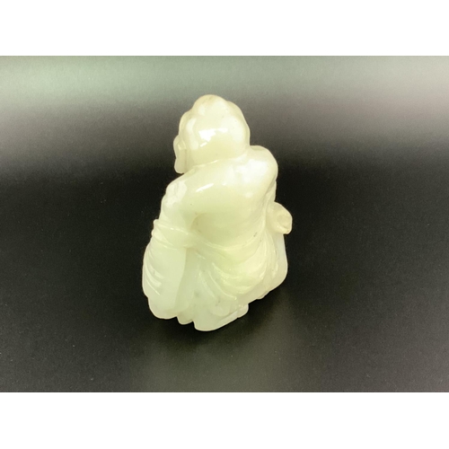 913 - A small carved jade figure of a Chinese deity seated upon a goat. 6cm.