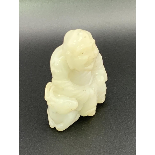 913 - A small carved jade figure of a Chinese deity seated upon a goat. 6cm.