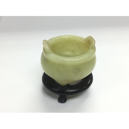 1139 - A small jade pot on a carved hardwood stand, total approx height 6cm. Shipping category B.