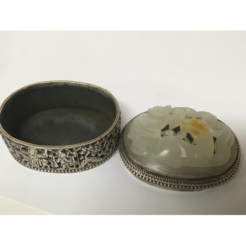 1030 - A Chinese white metal and jade mounted box of oval shape with a detachable lid the side with blind f... 