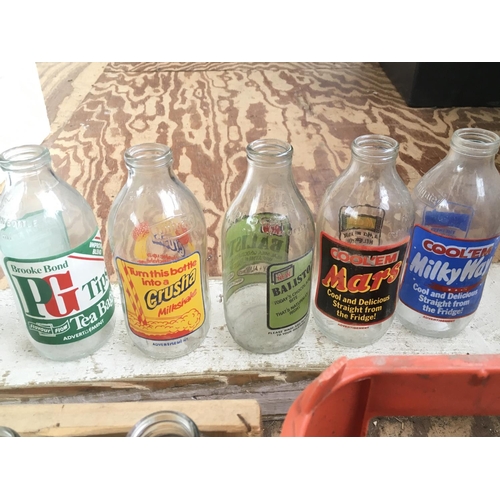 1345 - A collection of vintage Unigate milk bottles with various advertisements. Postage category D