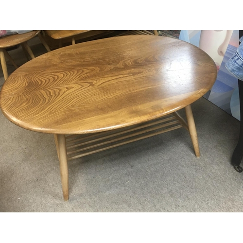 1525 - A Ercol occasional table the oval top on turned legs United by a under tier .