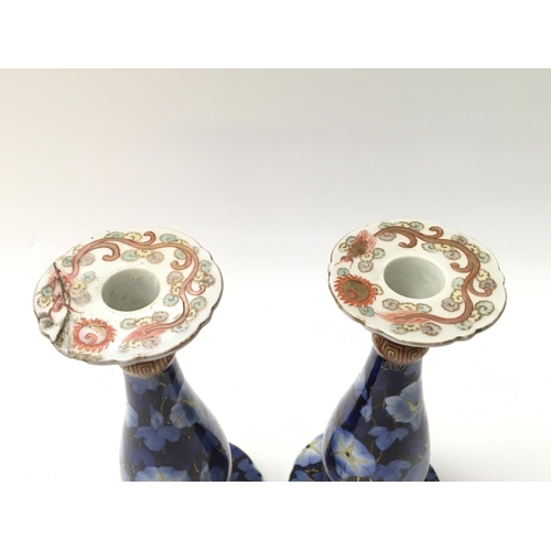 1008 - A pair of Japanese candle stick holders. One with repair to the top. 19cm tall.Postage D