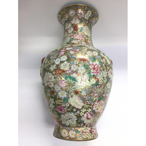 1030 - A large hand painted vase with heavy floral decoration on a gold coloured ground with animal head fa... 