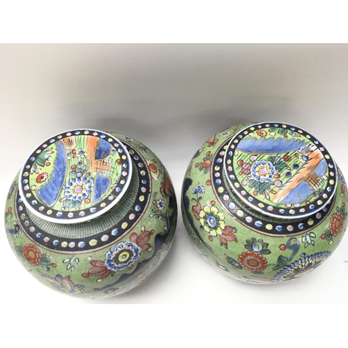 1054 - A pair of Chinese ginger jars with covers, decorated with flowers, butterflies on a green ground. 23... 