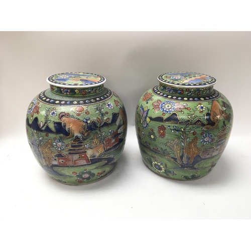 1054 - A pair of Chinese ginger jars with covers, decorated with flowers, butterflies on a green ground. 23... 