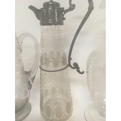 1290 - A glass claret jug with silver plated mounts and etched sides and two other etched jugs .