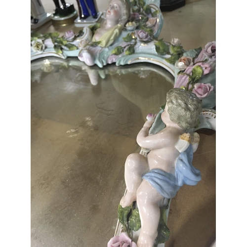 1341 - A German porcelain mirror with cherubs and flowers. 20cm