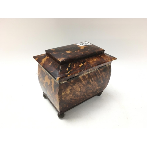 989 - A tortoiseshell tea caddy with hinge lid enclosing 2 compartments. On brass circler feet. 15cm x 16c... 