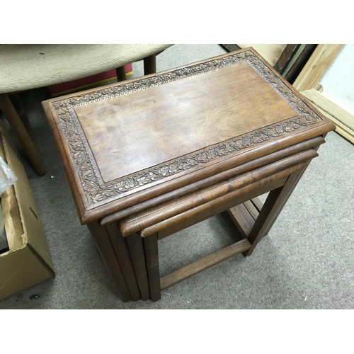 1264 - A nest of walnut tables with carved design, 46cm tall.