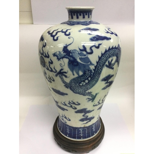 805 - A large blue and white baluster vase decorated with a dragon chasing a pearl raised on a hardwood st... 