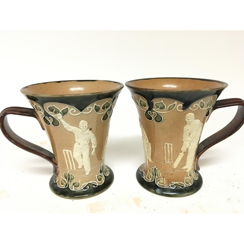 959 - Two Matching Lambeth Doulton stoneware mugs decorated with raised cricket figures impressed marks to... 