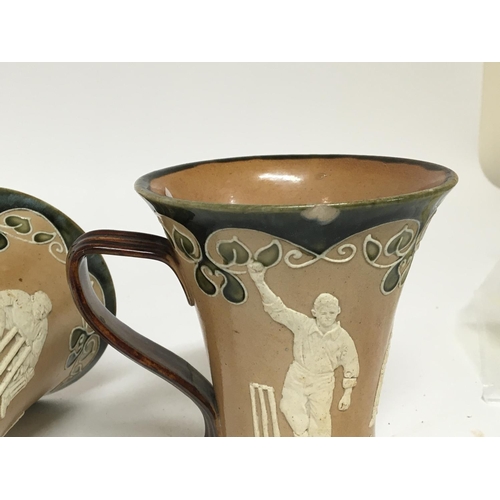 959 - Two Matching Lambeth Doulton stoneware mugs decorated with raised cricket figures impressed marks to... 